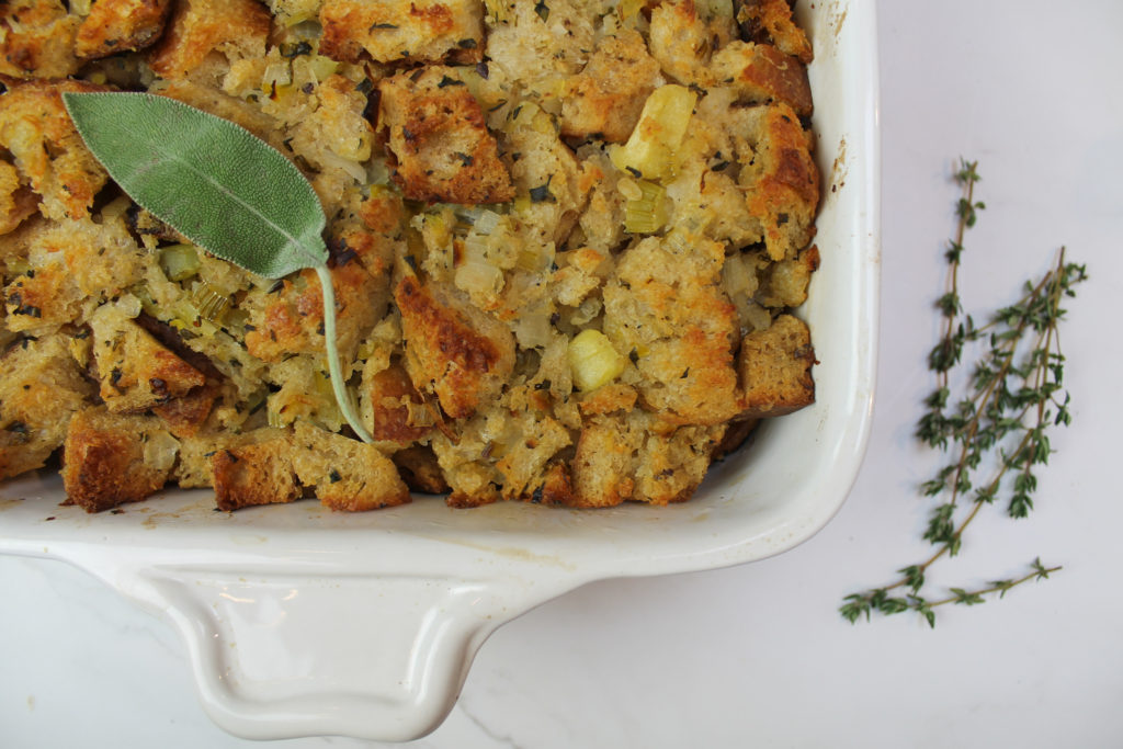 sourdough stuffing in white baking dish with thyme and sage