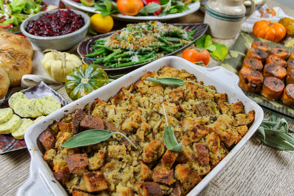 stuffing on thanksgiving table with butter, green beans, sweet potatoes, cranberry sauce