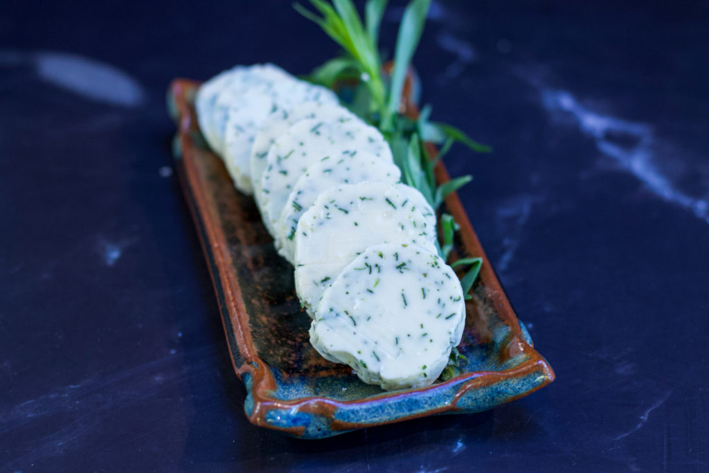 tarragon compound butter on serving tray with sprig of tarragon