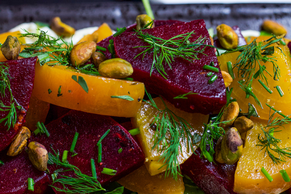 beet salad topped with herbs and pistachios