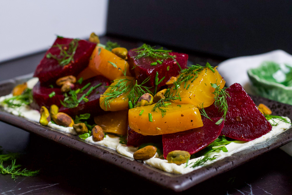 beet salad topped with herbs and pistachios