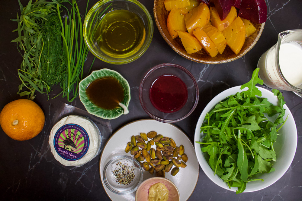 beet salad ingredients: herbs, orange, goat cheese, oil, vinegar, orange juice, arugula, beets and pistachios