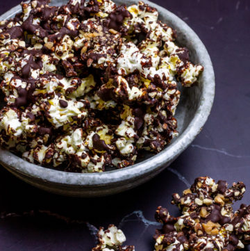 chocolate popcorn with toffee and almonds in grey bowl on black marble counter