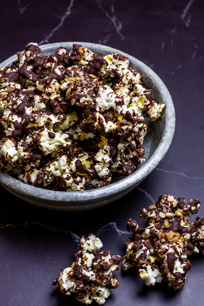 chocolate toffee popcorn with almonds in grey bowl on black marble counter