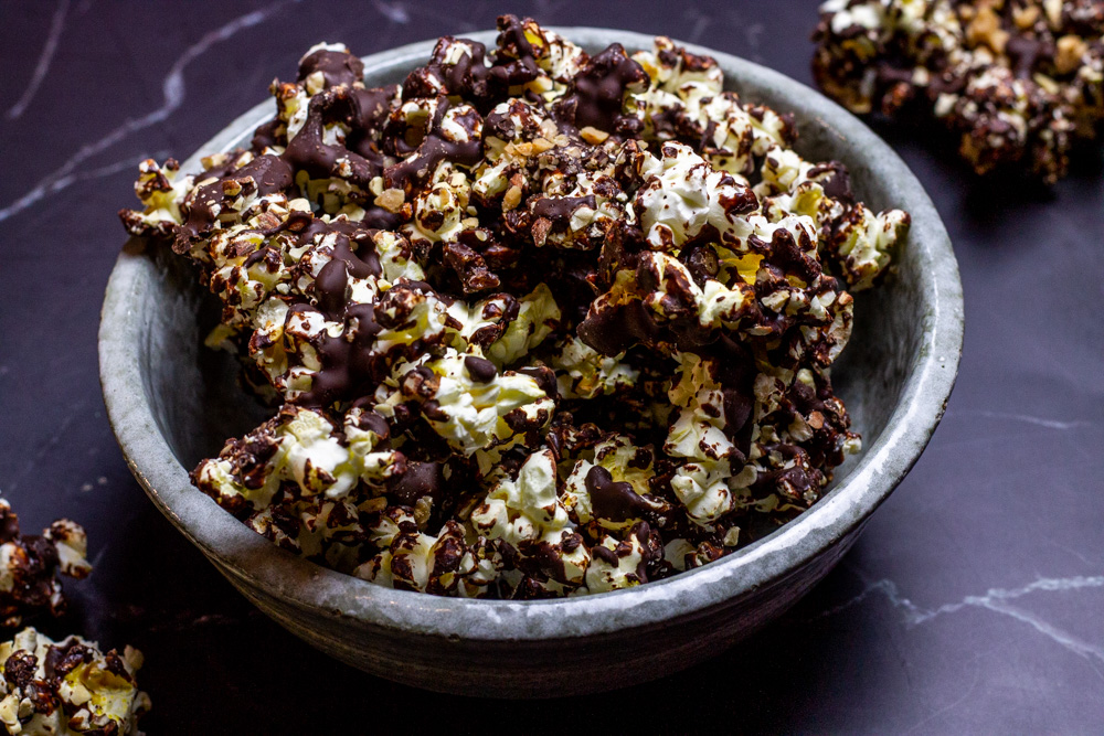 chocolate toffee popcorn with almonds and sea salt in grey bowl