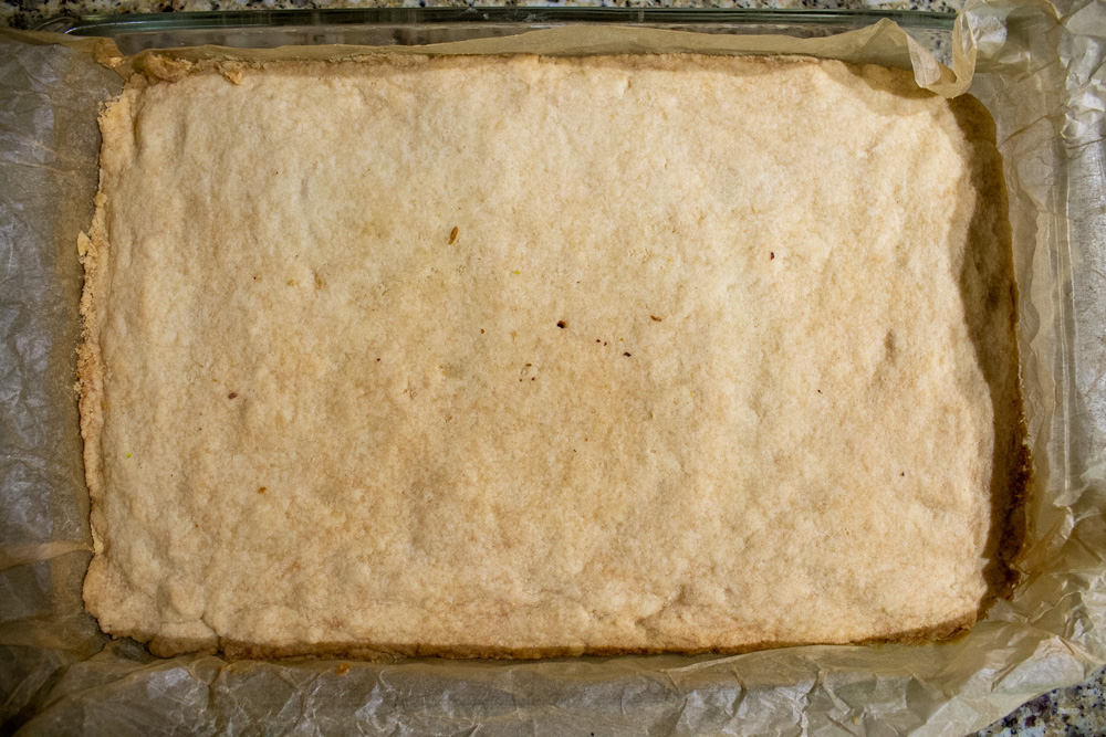 baked, golden shortbread layer in parchment in baking pan