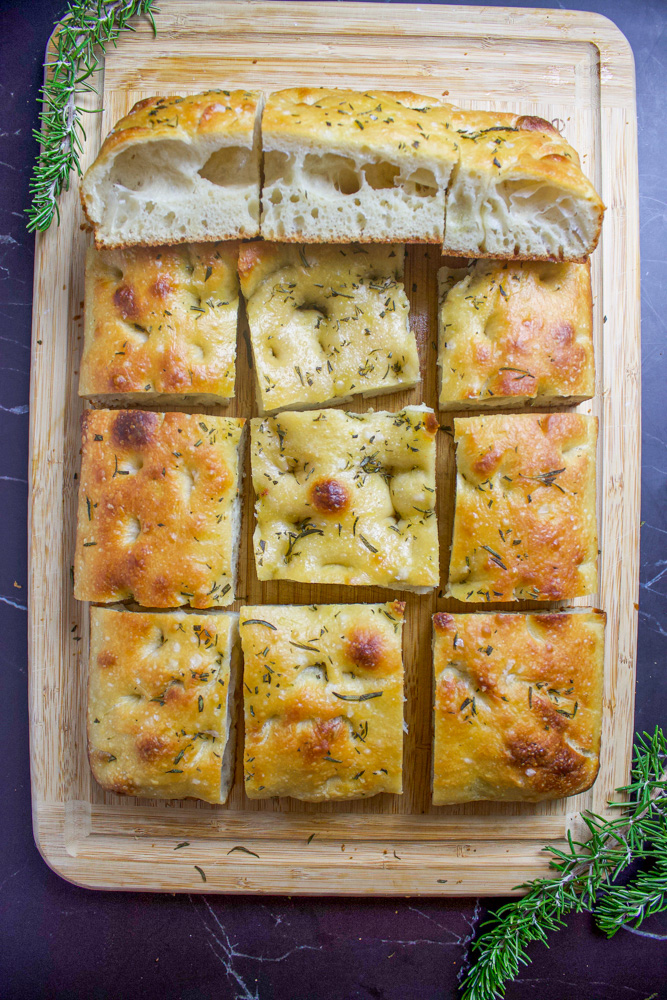 rosemary sourdough focaccia on cutting board with rosemary sprigs