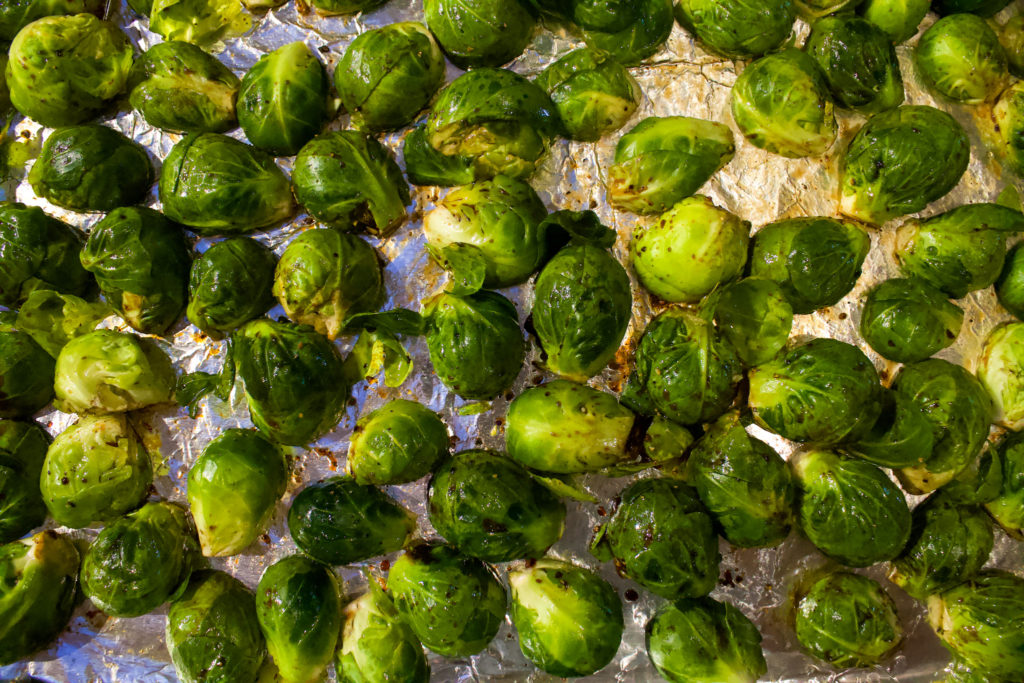 brussels sprouts on a tray with olive, salt, and pepper