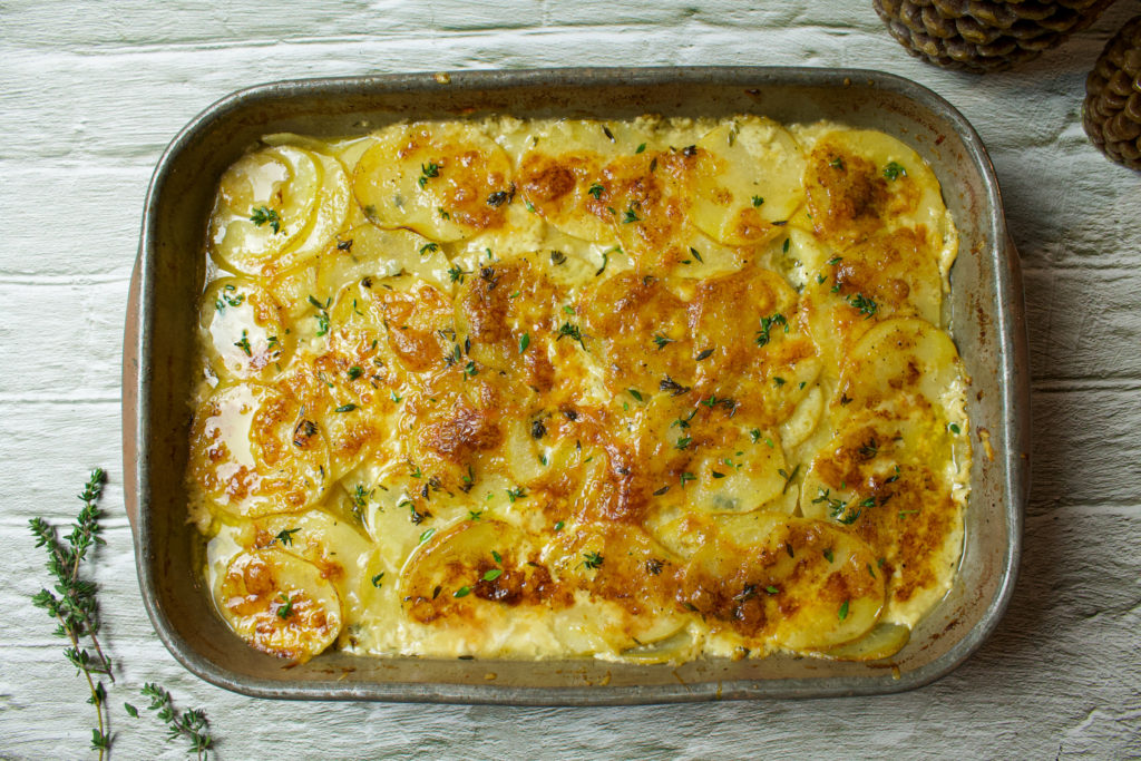 scalloped potatoes in a baking dish topped with thyme