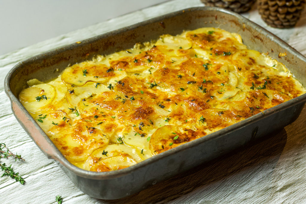 scalloped potatoes in a baking dish topped with thyme